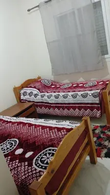 two beds in a room with a chair and a table at La maison verte in Fès