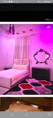 a pink room with a bed and a table at Location de vacance in Azrou