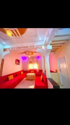 a living room with a red couch and a table at Location de vacance in Azrou