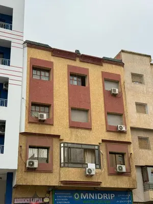 a tall building with windows and air conditioners at hôtel kawtar in Meknès