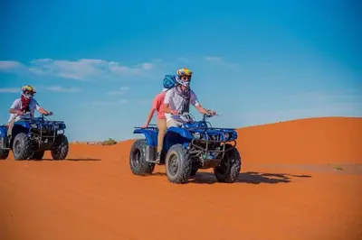 two people riding on quad bikes in the desert at Merzouga Solace Luxury Camp in Merzouga