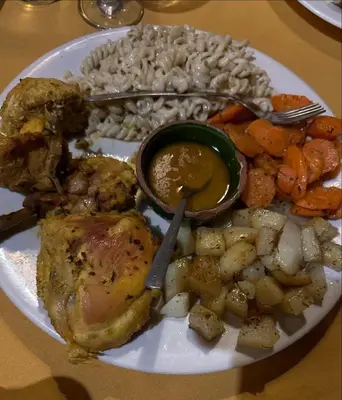a plate of food with chicken and vegetables on a table at Merzouga Solace Luxury Camp in Merzouga