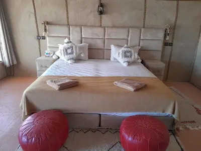 a bedroom with a large bed with red pillows at Merzouga Solace Luxury Camp in Merzouga