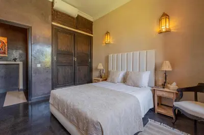a bedroom with a large white bed and a chair at Villa Chocolat Deluxe in Marrakech