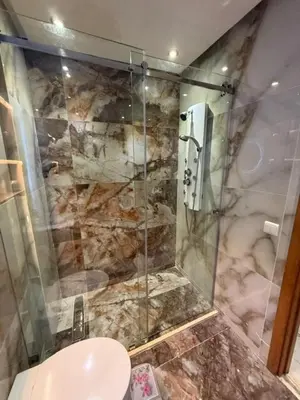 a bathroom with a glass shower with a toilet at Un bel appartement in Oulad Akkou