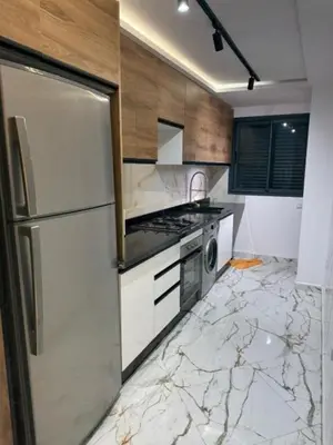 a kitchen with a marble floor and a refrigerator at Un bel appartement in Oulad Akkou