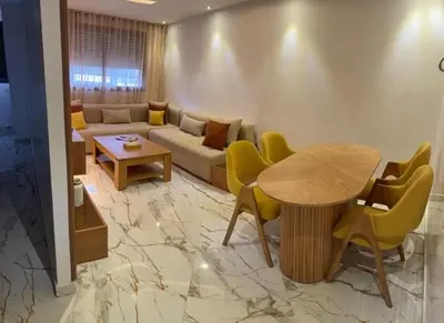 a living room with a couch and a table and chairs at Un bel appartement in Oulad Akkou