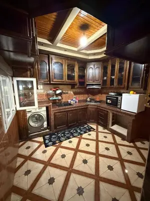 a kitchen with wooden cabinets and a tile floor at Maison vacancier in Oulad Akkou