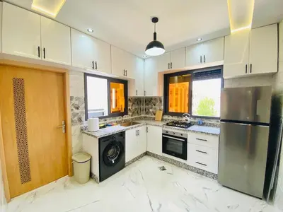 a large kitchen with white cabinets and a dishwasher at Appartement 2 chambres 1 salon in Azrou