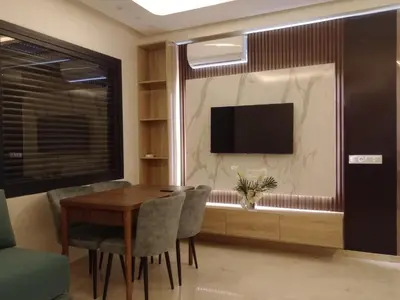 a dining room with a table and chairs and a television at Résidence les princesses champs de course in Fès