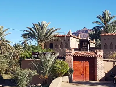 a house in the middle of the desert with palm trees at Rose du Sable in Agdz
