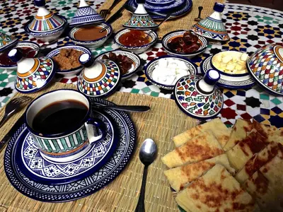 a table with plates of food and a cup of coffee at Riad Toyour- Riad of birds in Fès