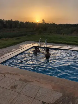 two people in a swimming pool at sunset at Villa Lina in Meknès