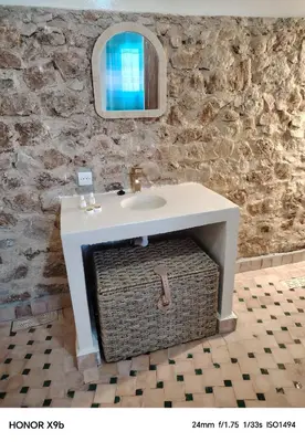 a bathroom with a sink and a wicker basket under it at Ferme d'hôtes Aghbalou in Sefrou