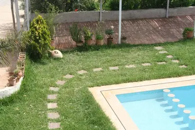 a dog laying in the grass next to a swimming pool at Ferme d'hôtes Aghbalou in Sefrou
