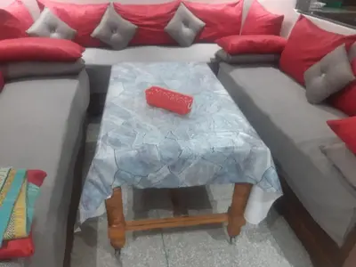 a table in front of a couch with a red pillow at Jolie Appartement Confortable - près de la plage in Oulad Akkou