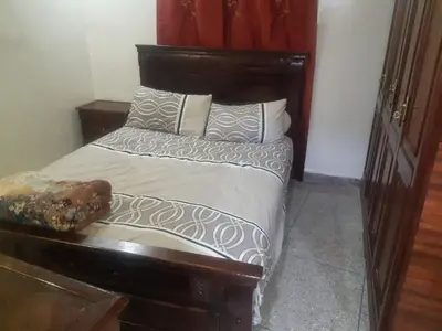 a bed with a wooden headboard in a room at Jolie Appartement Confortable - près de la plage in Oulad Akkou