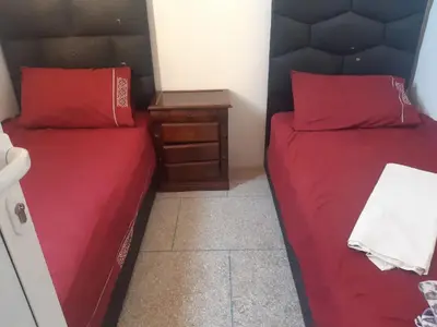 two beds in a room with red pillows and a night stand at Jolie Appartement Confortable - près de la plage in Oulad Akkou