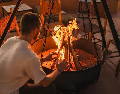 a man is cooking over a fire in a pot at Sahara Authentic Camp in Merzouga