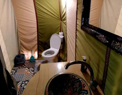 a bathroom with a toilet and a sink in a tent at Sahara Authentic Camp in Merzouga