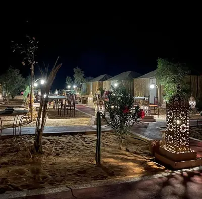 a park at night with tables and trees and lights at Sahara Authentic Camp in Merzouga
