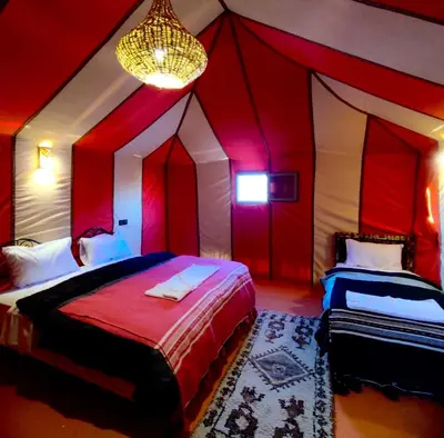 a bedroom with a tent with two beds and a chandelier at Sahara Authentic Camp in Merzouga