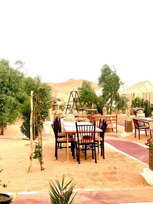 a table and chairs on a patio in the desert at Sahara Authentic Camp in Merzouga
