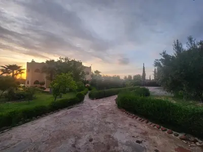 a path in a park with a building and trees at La dolce villa in Sidi Bouzguia