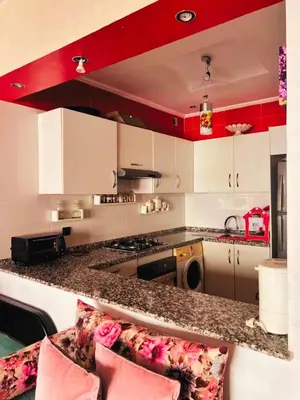 a kitchen with white cabinets and a counter with pink pillows at Apartment in Ouedlaou in Oulad Akkou
