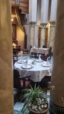 a dining room with tables and chairs in a building at Riad Victoria in Fès
