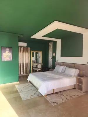 a bedroom with a large bed with a green wall at Auberge rahha