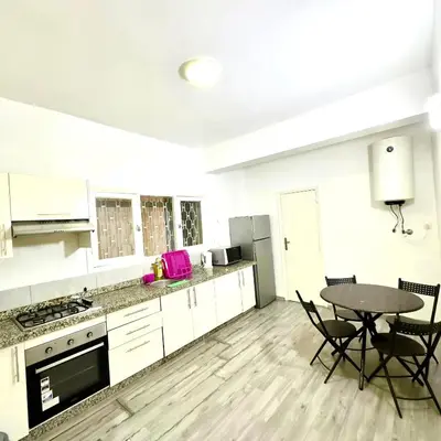 a kitchen with white cabinets and a table and chairs at Appartement centre ville avec Wifi 100Mo in Fès