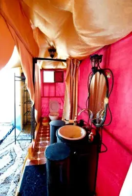 a bathroom with a sink and a red wall at Merzouga Lovely Luxury Camp in Merzouga