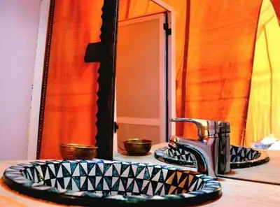 a bathroom sink with a faucet in front of a mirror at Merzouga Lovely Luxury Camp in Merzouga