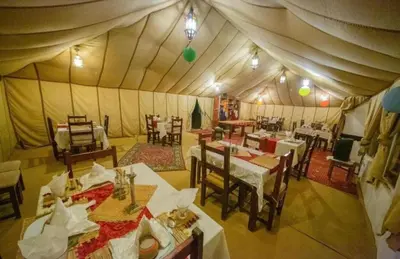 a dining room with tables and chairs in a tent at Merzouga Lovely Luxury Camp in Merzouga