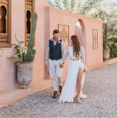 a man and a woman walking in front of a building at Riad Serai Merzouga in Merzouga