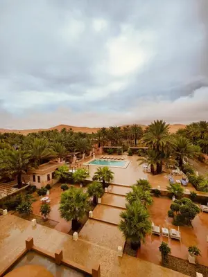 an aerial view of a resort with a pool and palm trees at Riad Serai Merzouga in Merzouga