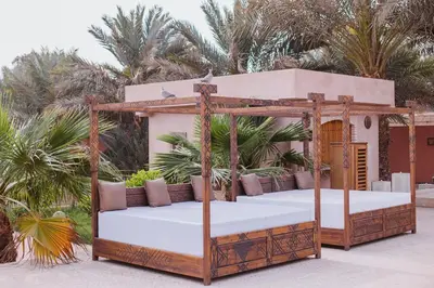an outdoor bed with a wooden bed frame at Riad Serai Merzouga in Merzouga