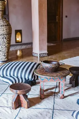 a room with a bowl on a table and two stools at Riad Serai Merzouga in Merzouga