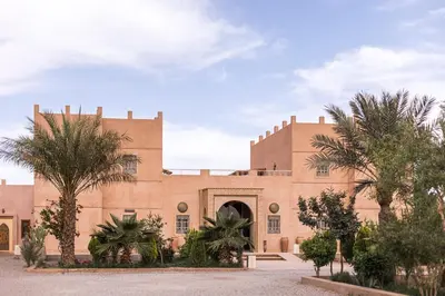 a building with palm trees in front of it at Riad Serai Merzouga in Merzouga