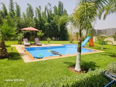 a swimming pool in a yard with a palm tree at Villa in Meknès