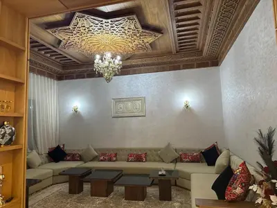 a living room with a couch and a chandelier at Villa à louer in Oulad Akkou