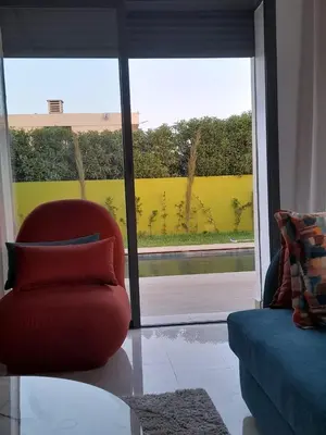 a living room with a red chair and a large window at Villa à louer in Oulad Akkou