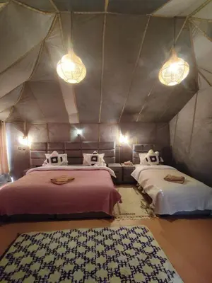 a room with two beds in a tent with lights at ChariF Luxury Camp in Rissani