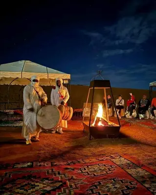 a group of people standing around a fire at Luxury sahara in Merzouga