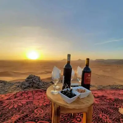 two bottles of wine and glasses on a table in the desert at caravanmaroc in Er Rachidia