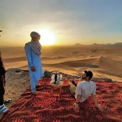 two men sitting on the ground in the desert at caravanmaroc in Er Rachidia