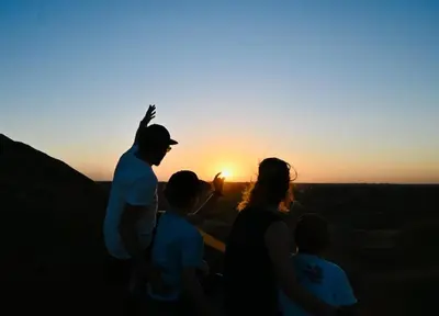 a group of people watching the sunset in the desert at caravanmaroc in Er Rachidia