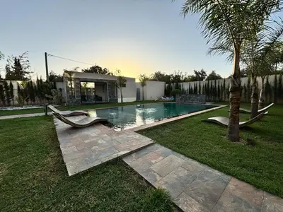 a swimming pool in a yard with a palm tree at Villa Atlas in Aghmat