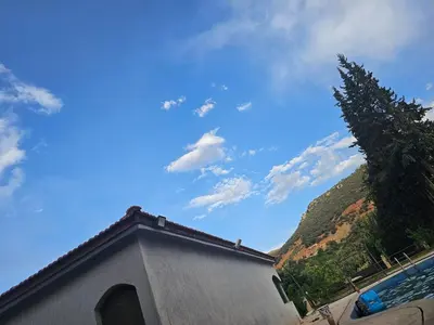 a blue sky with a building and a mountain at Ferme avec piscine et vue panoramique in Khenifra